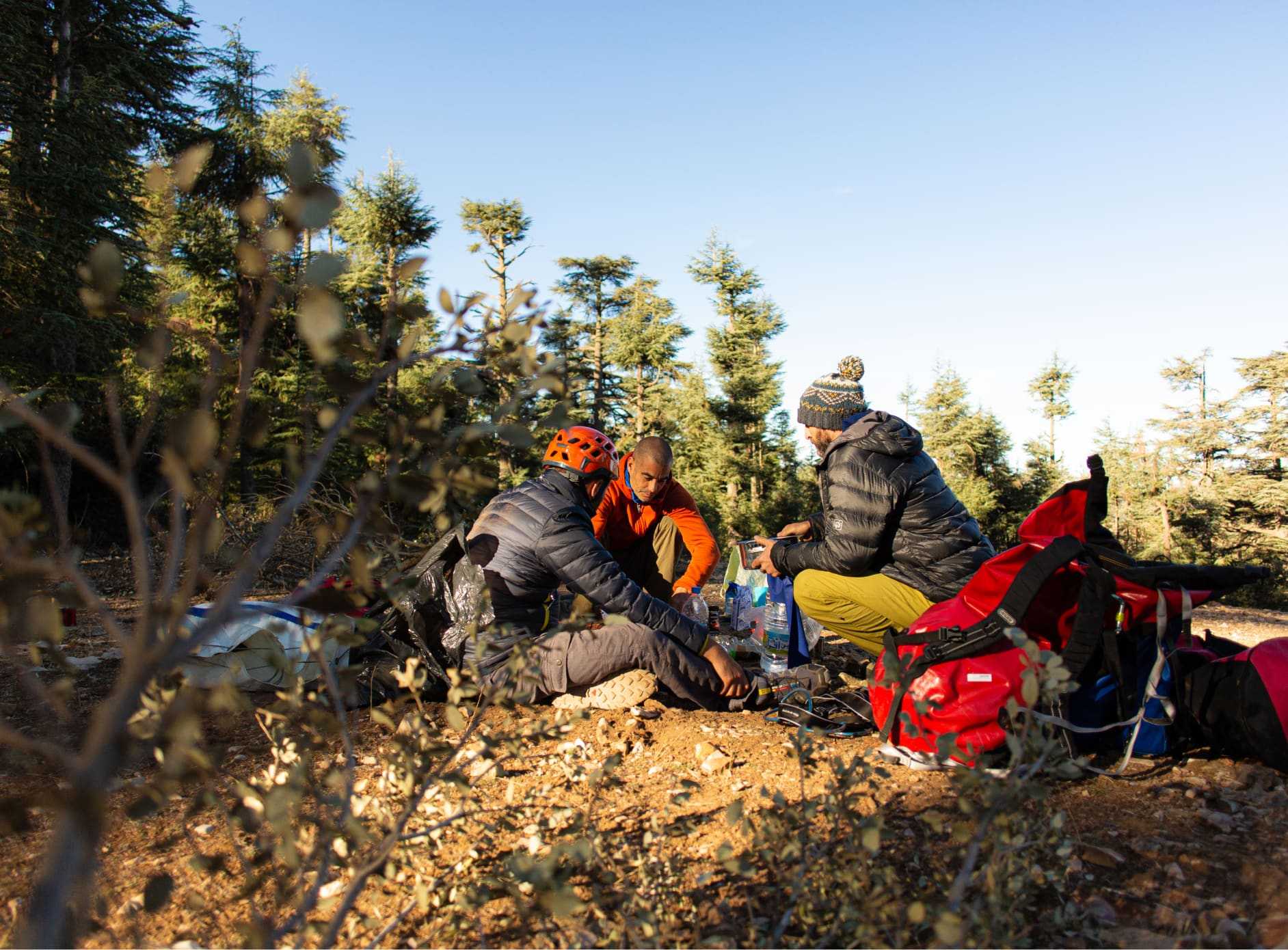 Three men sat under trees making breakfast at the top of the Atlas Mountains in Morocco.